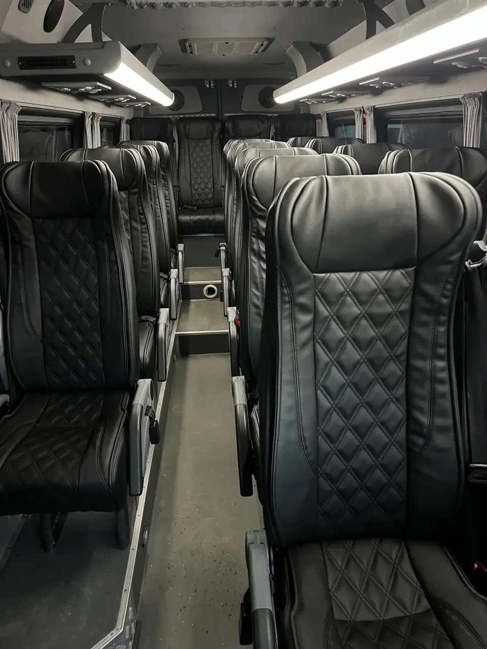 Khoang khách xe 19 chỗ Mercedes-Benz Sprinter với ghế da đen chần trám, đèn trần và giá để đồ